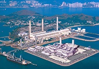 An aerial view of the Lamma Power Station in Hong Kong is surrounded by a large body of water and a city scene.