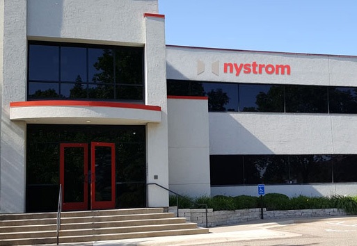 An exterior view of Nystrom Headquarters, with colors of cream red and black, is seen on the building with a sidewalk and staircase in view.