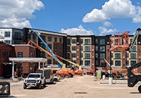 A residential construction scene with tall buildings and construction vehicles in view.